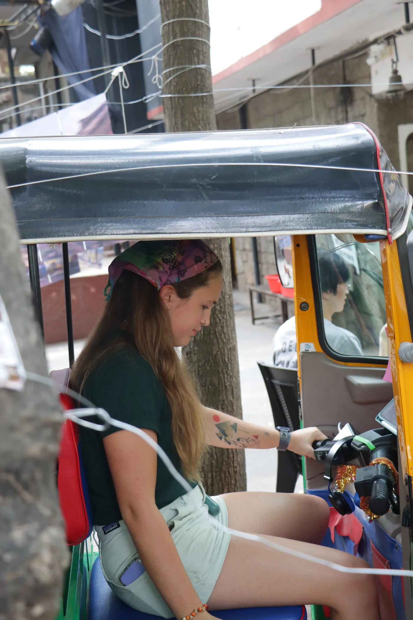 A visitor in a patterned bandana standing beside the auto with string in her hands.