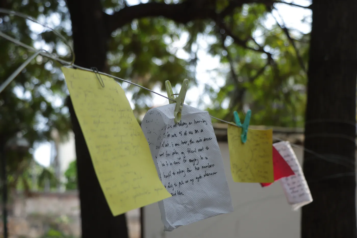 A close view of handwritten notes pegged to a line, one filled edge to edge with writing.