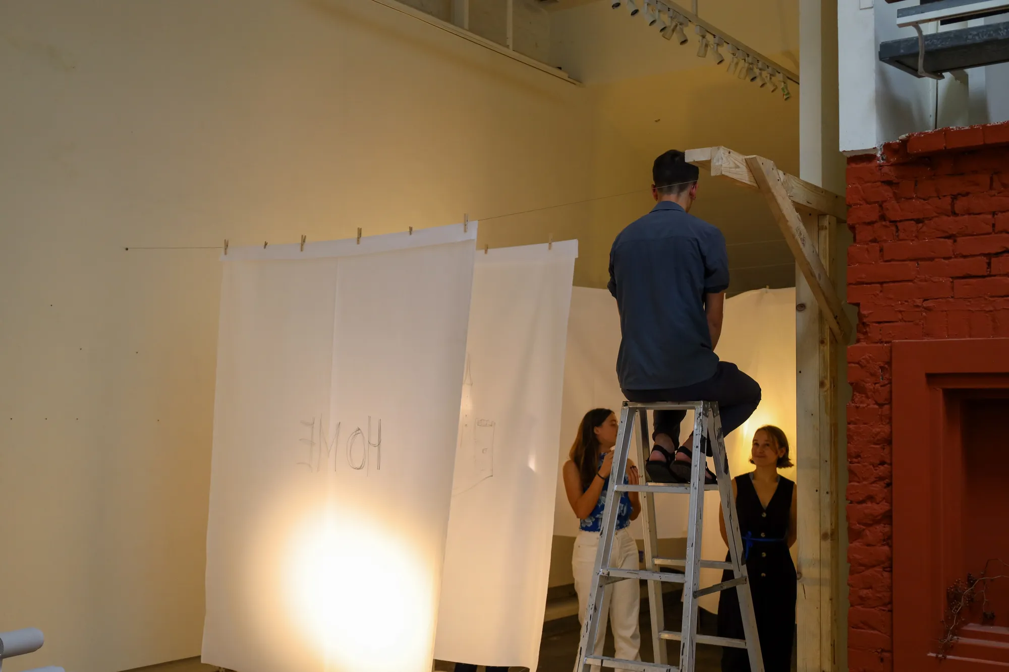 Sheets of semi-transparent fabric hung in a row down the room, each drawn on, forming a tunnel.